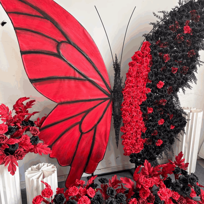 Artistic Red and Black Butterfly Backdrop with Lush Rose Arrangements