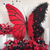 Artistic Red and Black Butterfly Backdrop with Lush Rose Arrangements