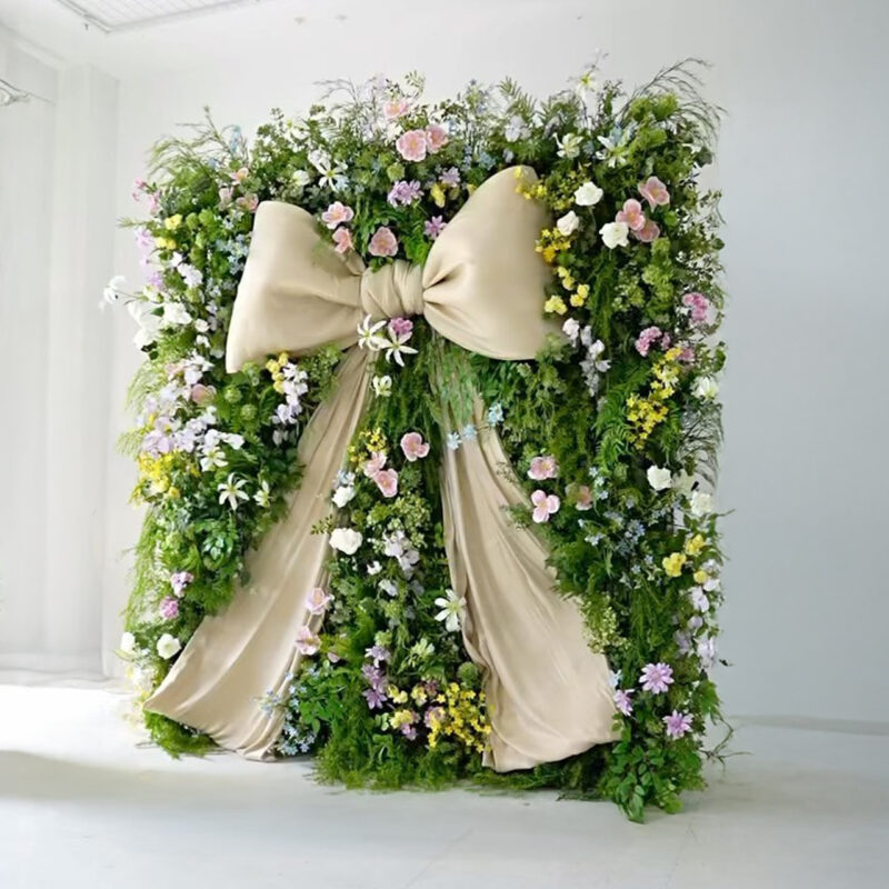 Elegant Green Wildflower Wall with Silk Flowers, Giant White Bow, and Organza for Outdoor Wedding Decor