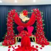 Romantic Wedding Arch with Red Roses, Green Leaves, and Elegant Drapery